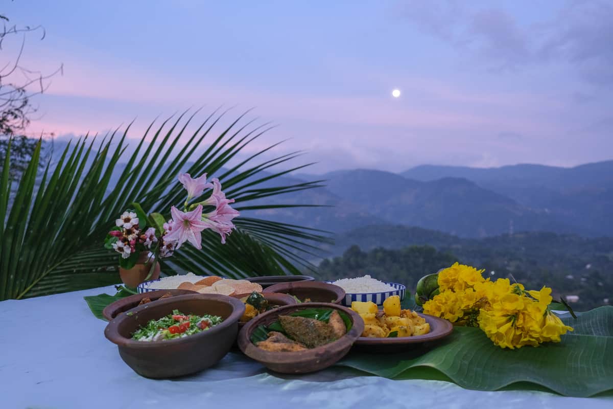 Dinner laid out on the terrace at dusk: curries in clay pots, rice and flowers from the garden